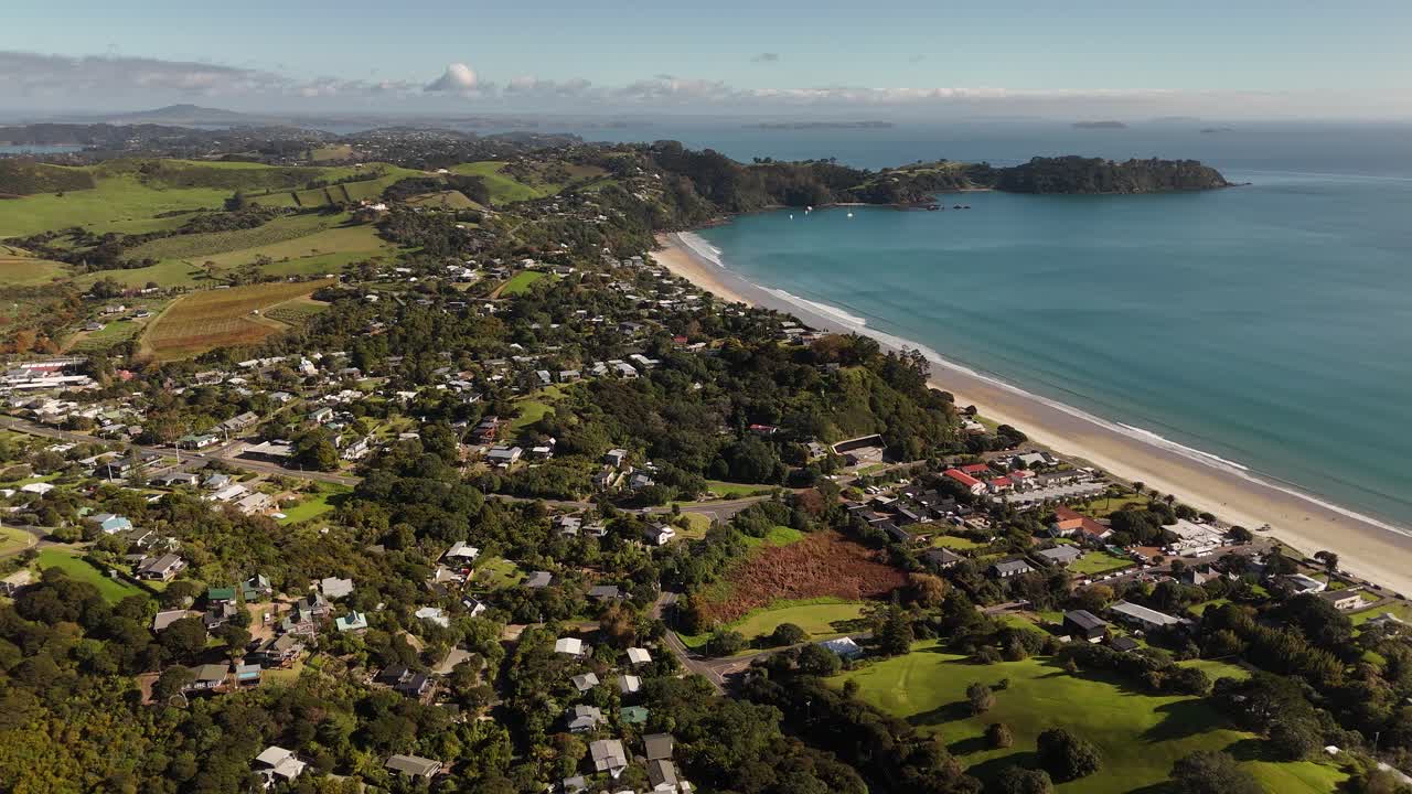 Captivating 4K drone footage showcasing the residential area of Waiheke Island's Onetangi region, featuring homes fronting the beautiful ocean.
