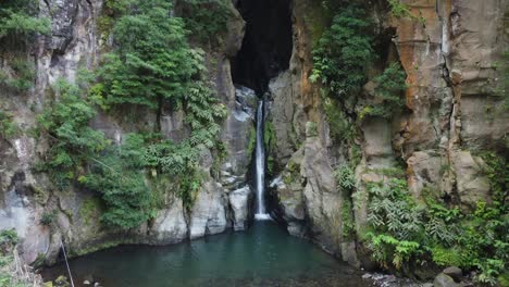 narrow waterfall flows out of slot canyon at salto do cabrito, azores