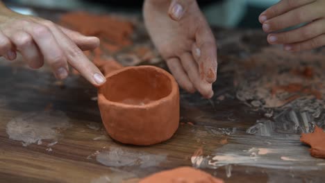 hands shaping clay pot