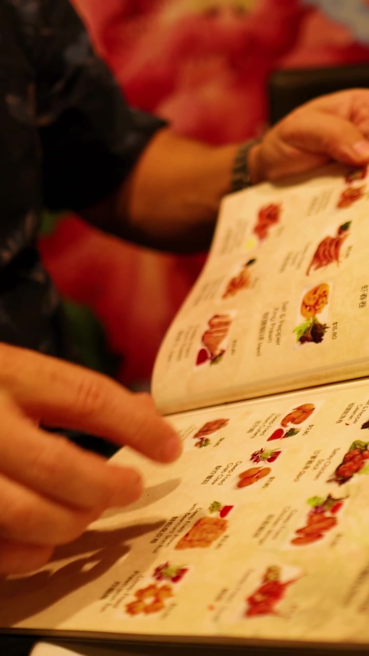 En person bladrer igennem en restaurantmenu og undersøger forskellige retter i et varmt oplyst miljø.