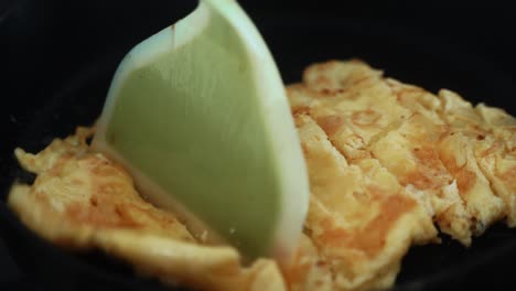 una toma de cerca crujiente, volviendo la tortilla en una sartén negra caliente, un huevo con tortilla de ognion, haciendo un video de desayuno 4k
