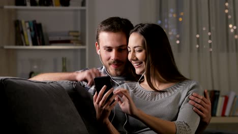 pareja feliz compartiendo auriculares viendo videos