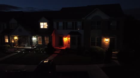 american suburban homes at night, porch lights glowing warmly, peaceful neighborhood scene. sense of safety, routine and quiet life as darkness falls over the residential street. aerial view. pa, usa