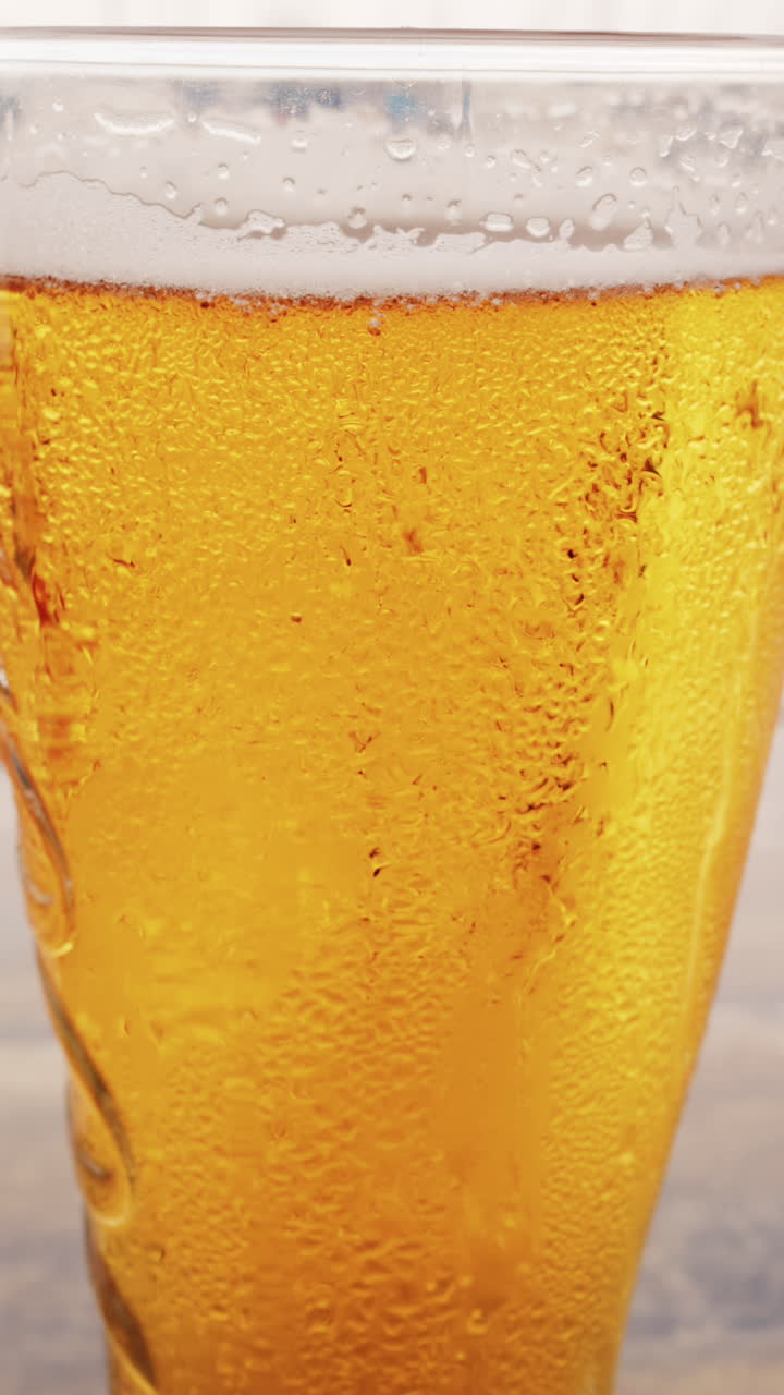 Close up of bubbles forming into foam in a beer glass. Vertical