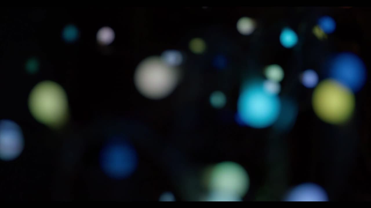 Luci bokeh colorate astratte e sfocate in movimento su uno sfondo scuro