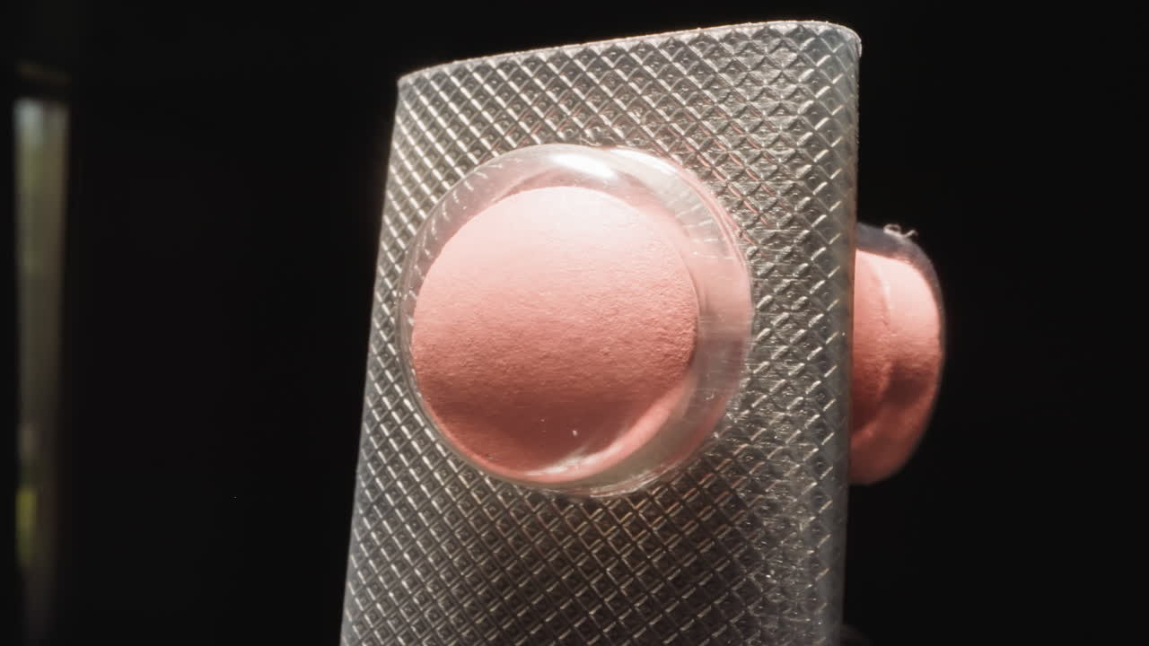 Curved blister with pink pills under transparent shell
