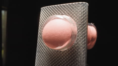 blister curvo con píldoras rosadas bajo una cáscara transparente