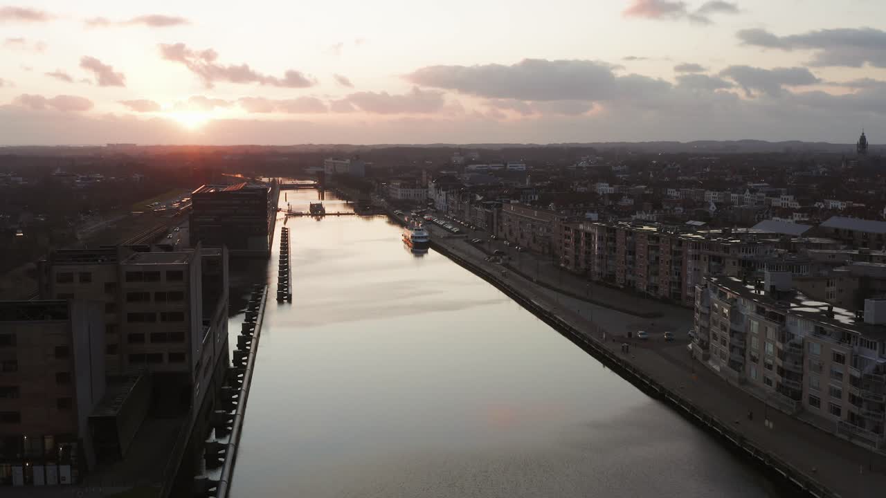 Slow aerial shot of a canal through a city during sunset. Drone shot
