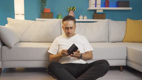 the man sitting by the wall looks at his empty wallet. broke.