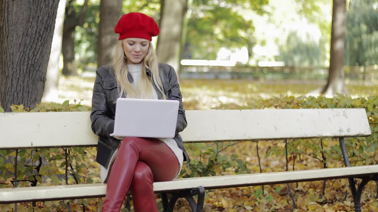 Smiling woman using laptop in park