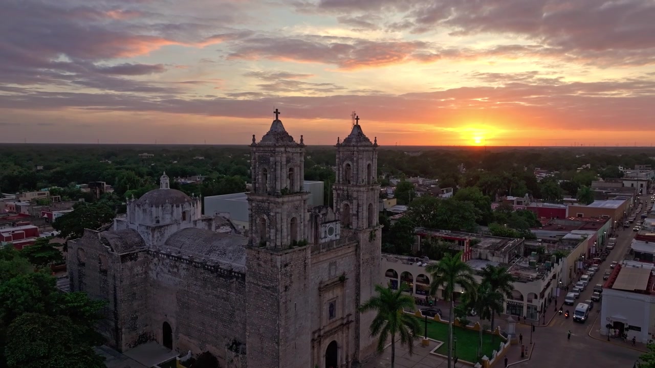 Valladolid, Yucatan, Meksika üzerinde parlayan gün batımı gökyüzüne karşı silüeti belirmiş San Bernardino manastırının havadan görünümü, tarihi kasaba alacakaranlığa karışıyor.