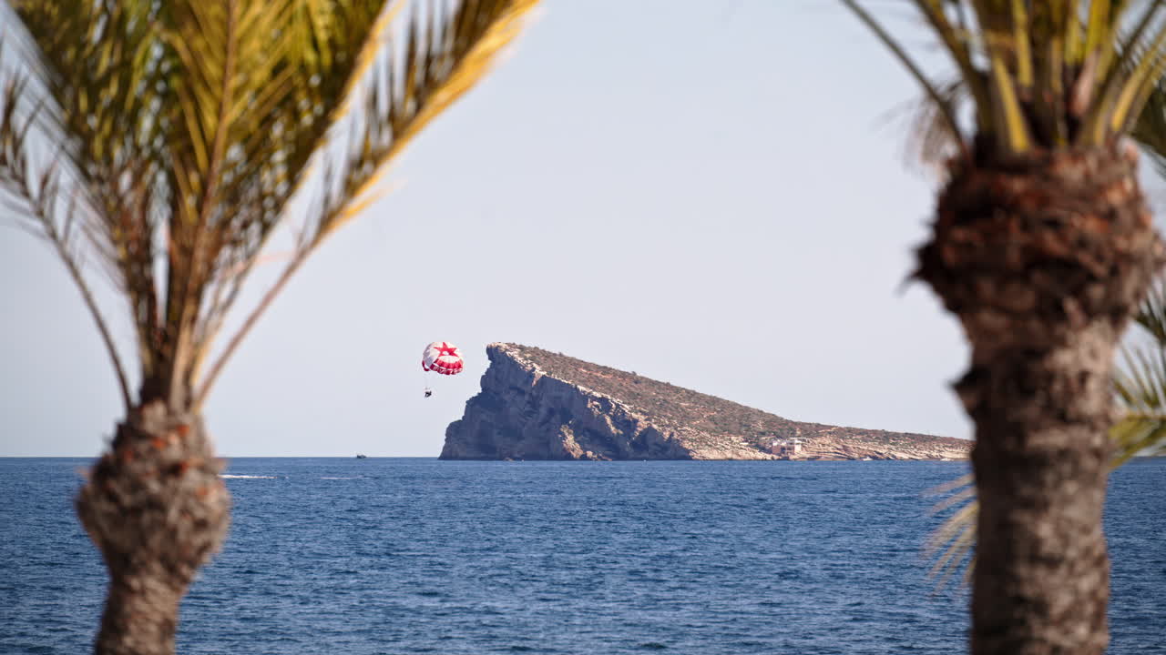 Benidorm Island framed by palms, seen from the seafront promenade in Benidorm, Alicante
