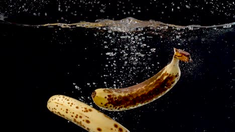 a set of ripe bananas being dropped into water in slow motion