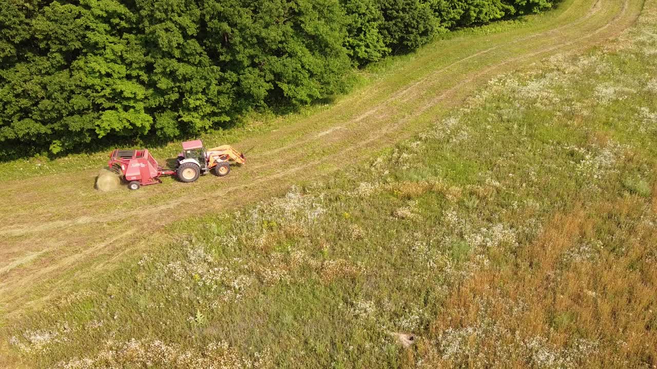 la empacadora redonda descarga fardos de heno frescos durante la cosecha agrícola en el condado de leelanau, michigan