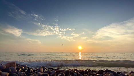 landing airplane above breaking waves on the sea at sunset in slow motion