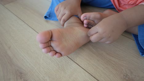 a toddler is sitting on the floor and playing with their feet.