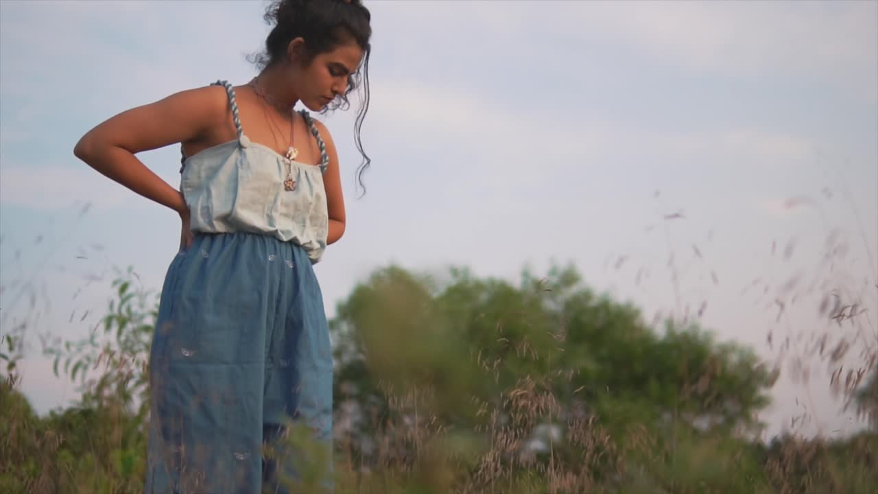 mujer joven en mono azul buscando algo en la hierba seca