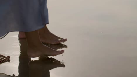 feet closeup of young caucasian couple strolling along seashore.