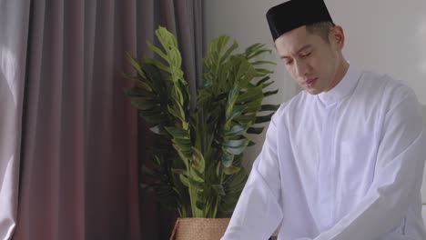muslim man sit reading the book and pray prayer by hand in the air in the home, belief quran culture