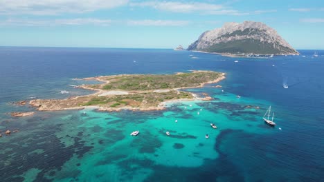 tavolara island and isola piana surrounded by boats and turquoise blue sea in sardinia, italy - aerial 4k circling