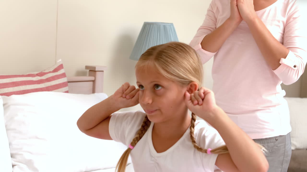 Bambina sconvolta che copre le sue orecchie mentre sua madre che grida