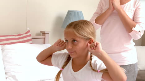 upset little girl covering her ears while her mother screaming