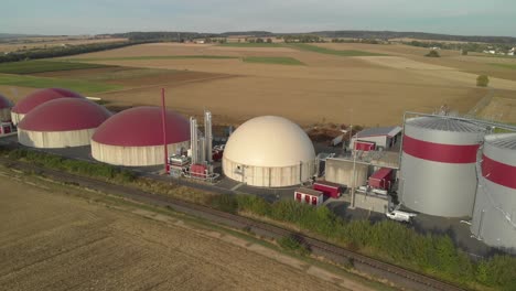 aerial view of a biogas plant surrounded by fields and countryside, bright daylight