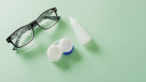 vídeo de gafas, caja de lentes de contacto y solución de lentes sobre fondo verde con espacio para copiar