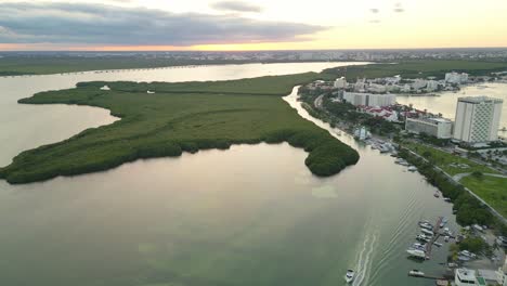Cancun’s lagoon, green mangroves, and luxury waterfront resorts at sunset, aerial view