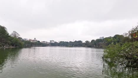 lago tranquilo con árboles y edificios lejanos