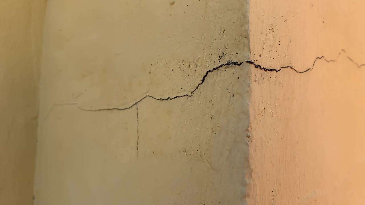 una grande crepa nel muro che mostra la crepa in dettaglio con un angolo, un buon videoclip per mostrare danni al muro o riparazioni domestiche necessarie