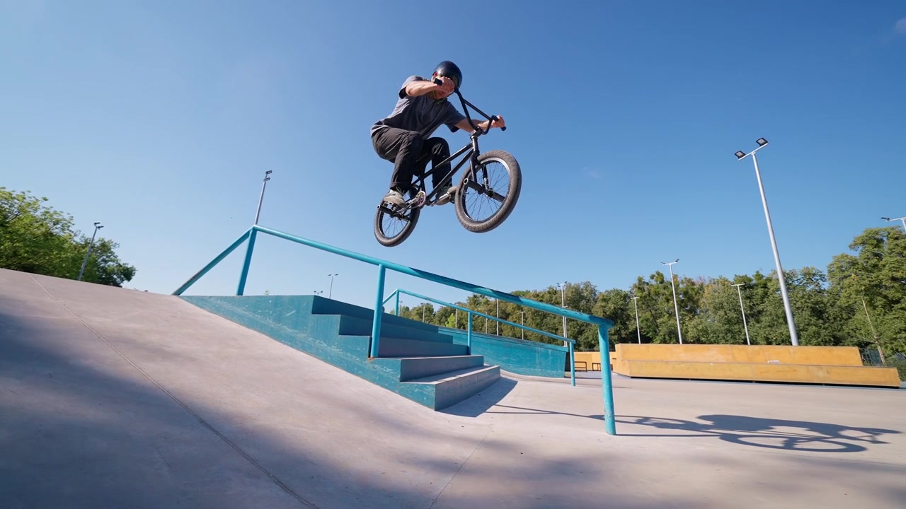 Ciclista BMX che salta sopra una ringhiera e delle scale in uno skatepark