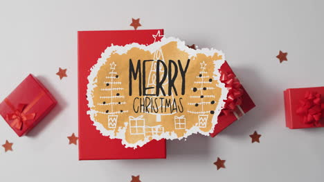 animation of merry christmas text over presents and christmas decorations on white background