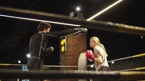 beautiful fit girl training in sport club. male boxer giving instructions at gym