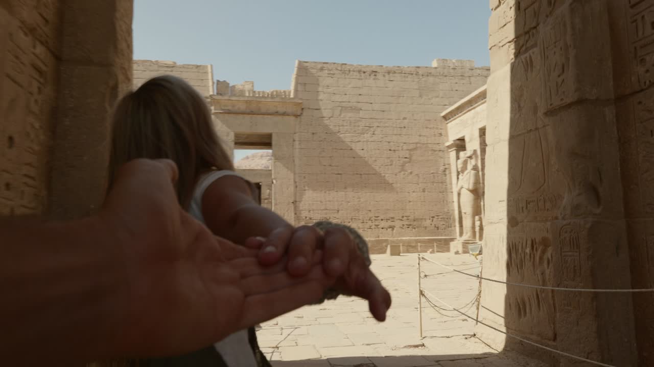 sígueme a egipto: una pareja joven de manos en la mano haciendo turismo del antiguo templo egipcio.