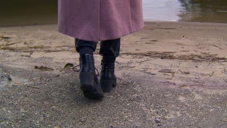 woman in pink coat walking by a river