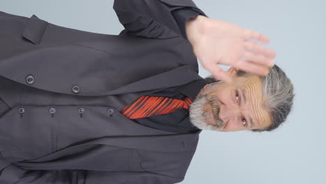 vídeo vertical de un viejo hombre de negocios saludando a la cámara.