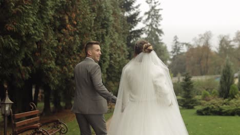 Lovely-newlyweds-caucasian-bride-groom-running-in-park,-holding-hands,-wedding-couple-family