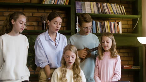 Young-teacher-and-students-singing-and-playing-christian-music