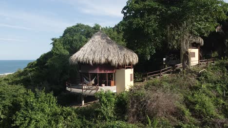 Drone-rises-through-the-trees-to-reveal-a-lonely-hut-in-the-rainforests-of-Tayrona,-Colombia