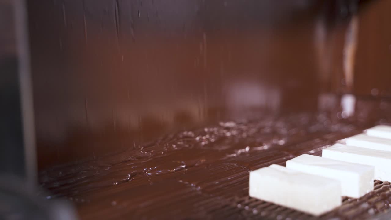 Covering candies with dark melted chocolate at the factory. Conveyor for the production of sweets. Automated product supply