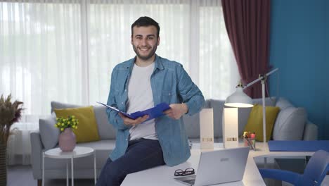 Cheerful-real-estate-agent-looking-at-camera-with-house-key-and-contract-papers.