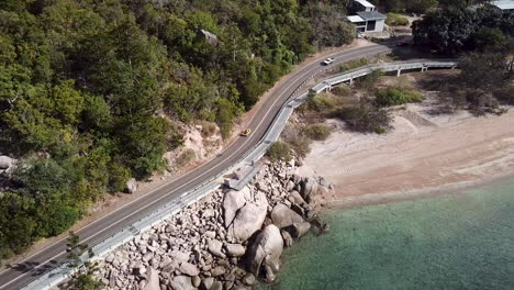 Luftaufnahme-Des-Klassischen-Strandbuggys-Mit-Offenem-Verdeck,-Der-Entlang-Der-Felsigen-Küstenstraße-Entlang-Der-Klippen-Neben-Kristallklarem-Tropischem-Wasser-Fährt