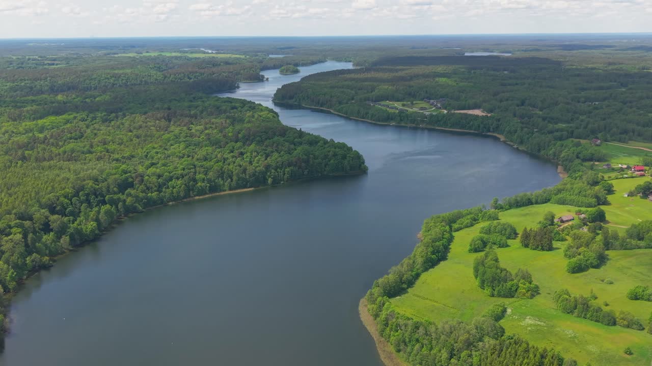 Vista aerea con drone di un fiume serpeggiante circondato da foreste verdi lussureggianti e campagna in una soleggiata giornata estiva.