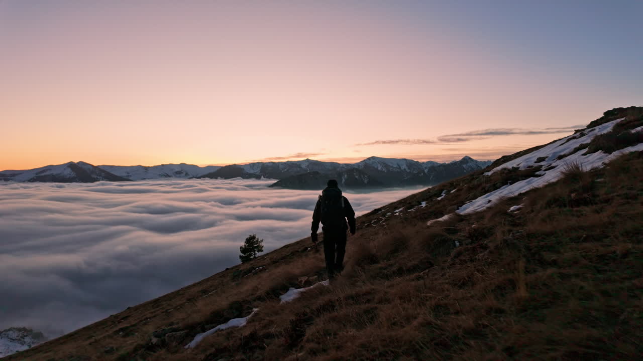 Hiker enjoys serene mountain sunrise above sea of clouds, awe-inspiring view