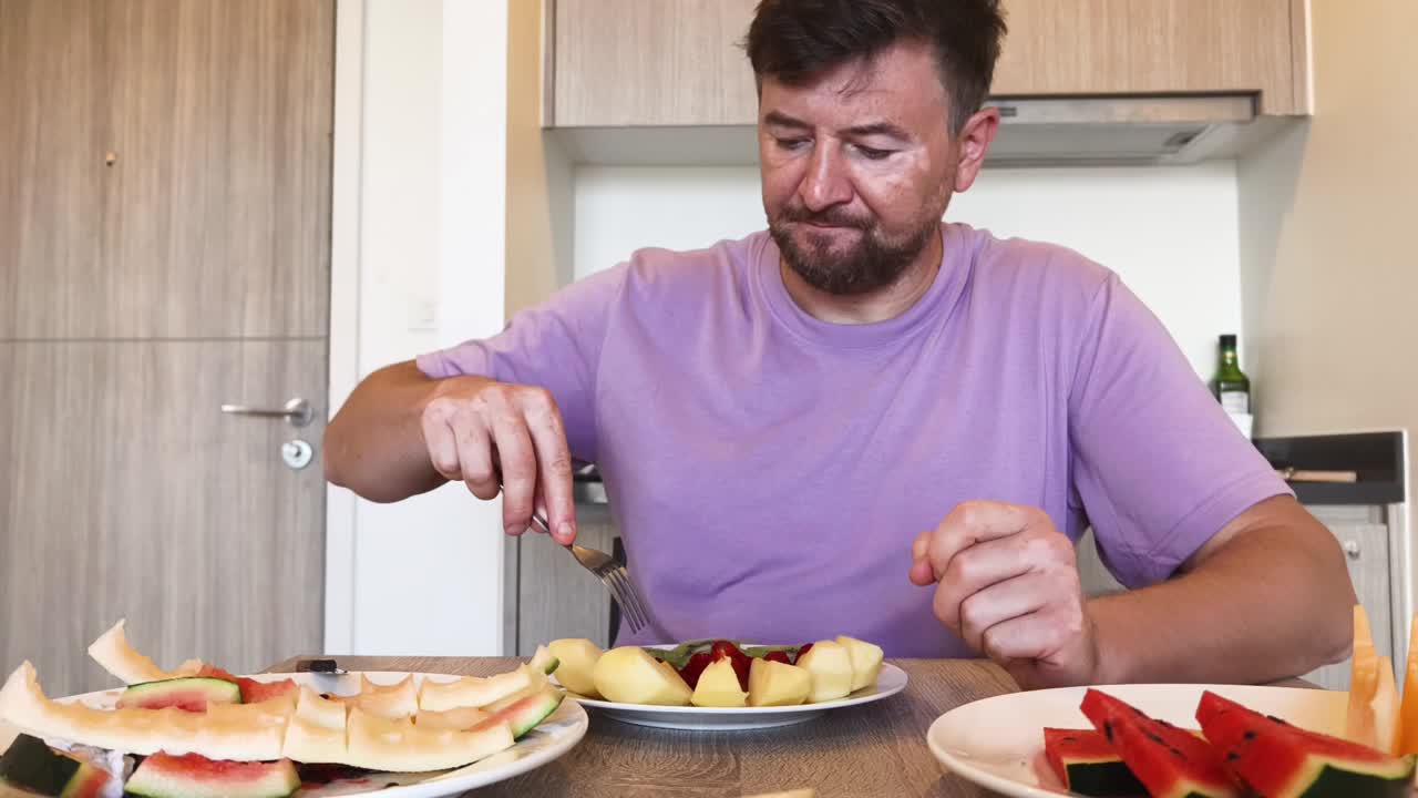 Man Eating Fresh Fruit in Kitchen