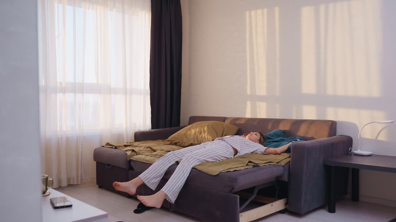 Calm Restful Afternoon, Woman Lying Peacefully On Cozy Sofa Bed, Exhausted Female In Pajamas Unwinding On Sofa, Relaxed Young Lady In Pajamas Enjoying Peaceful And Restful Afternoon At Home