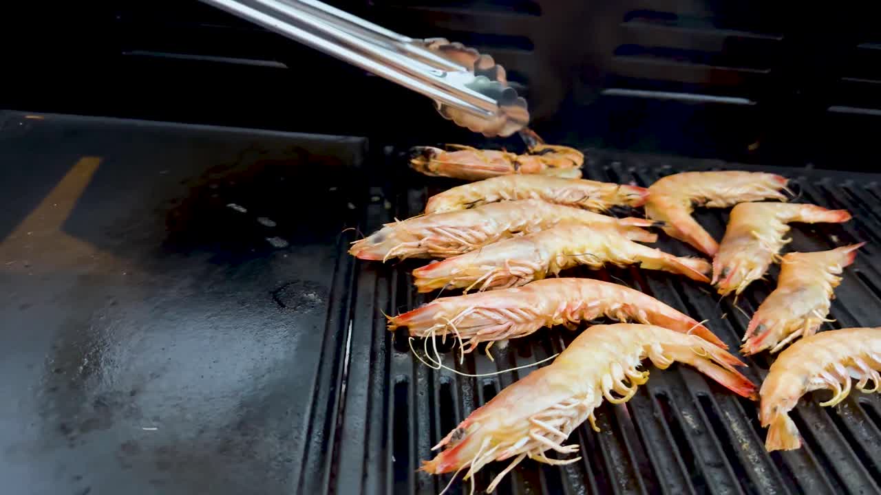camarones siendo asados con pinzas en la barbacoa