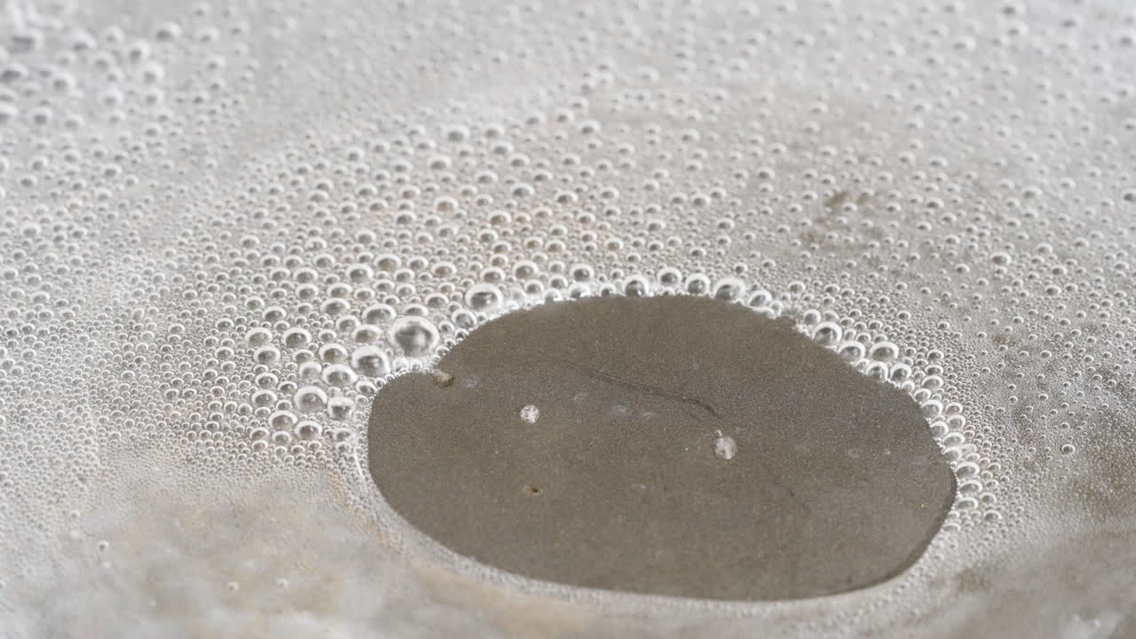Water boiling and evaporating steam from a Teflon Pan - macro