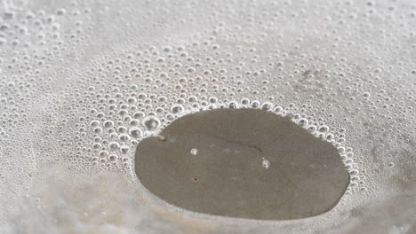 water boiling and evaporating steam from a teflon pan - macro